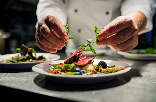 Chef adding the final flourish by adding some liquorice flavoured parsley to the dish. The dish is, pan fried pink duck breast onto a bed of parsnip puree with seasonal autumn vegetables and berries.